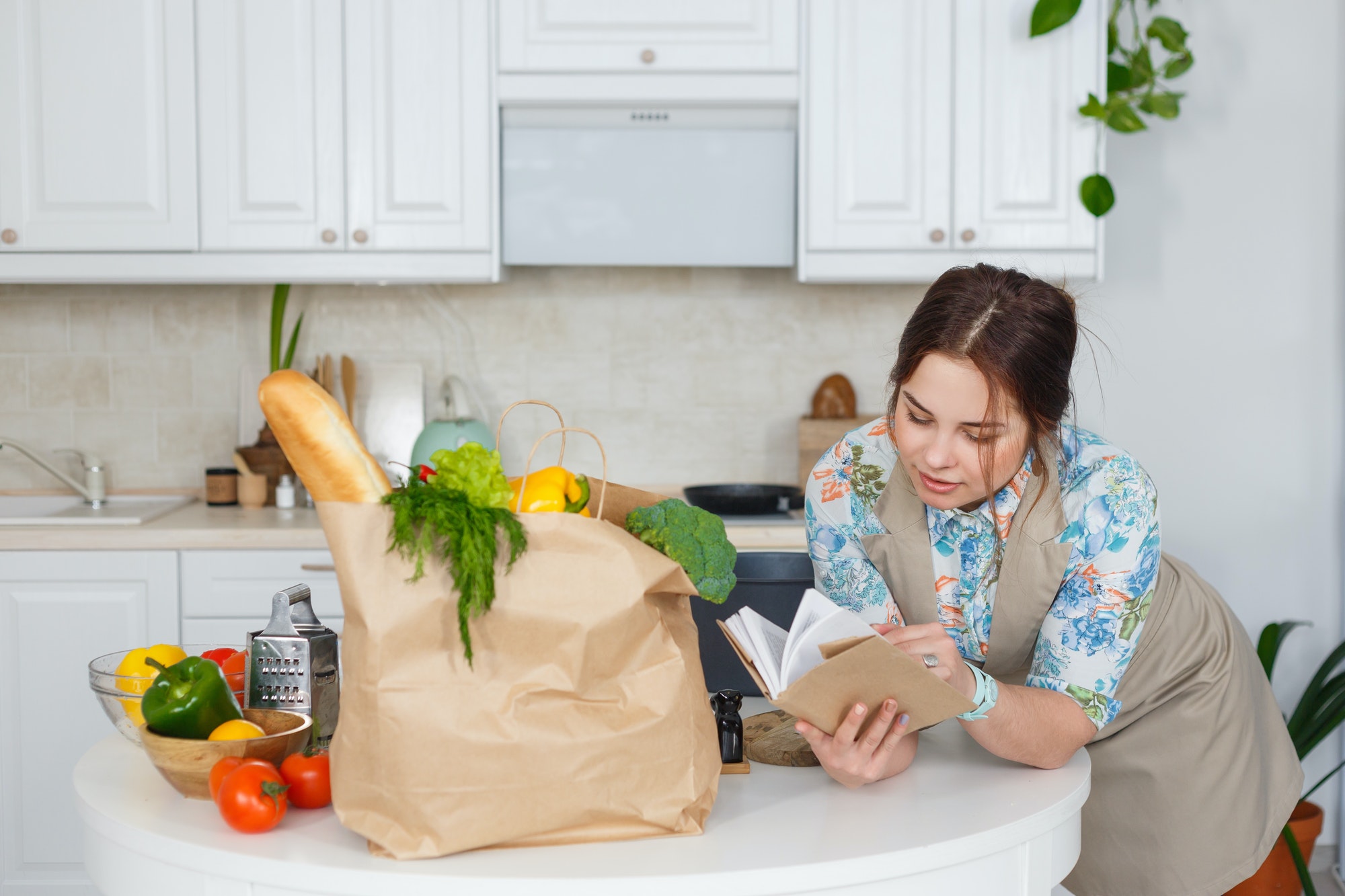 Young housewife with recipes book in the kitchen